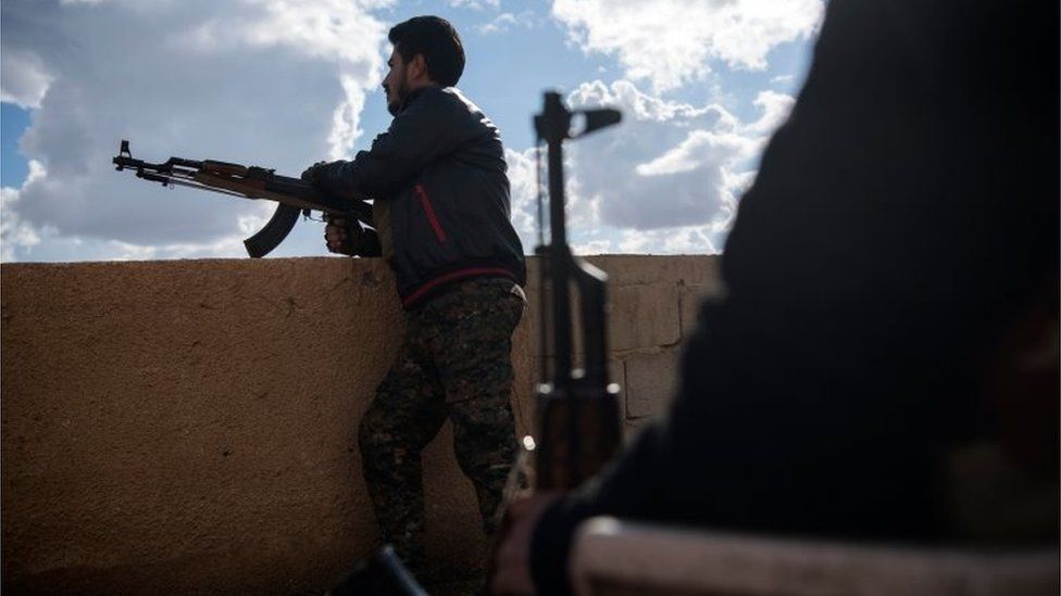A member of the Syrian Defence Forces stands guard on top of a building in the frontline Syrian village of Baghuz, on 17 February 2019