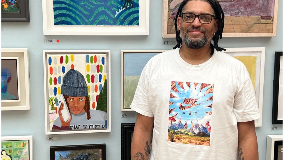 Errol Theunissen standing in front of paintings on a wall