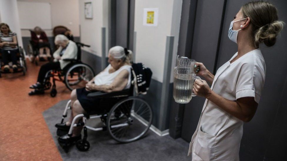 A medical staff member brings water to residents in a retirement home in Bordeaux