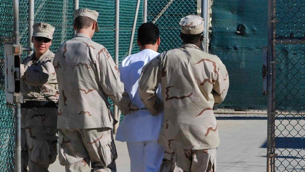 US Navy guards escort a detainee through Camp Delta at Guantanamo Bay naval base on 10 June, 2008