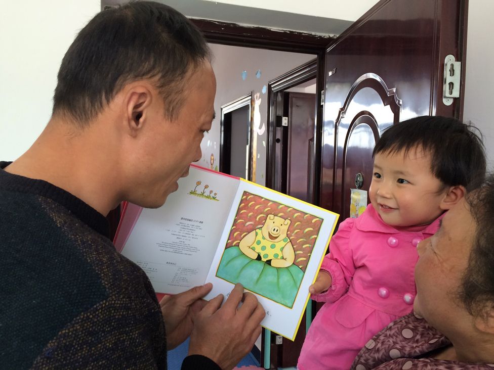 Family planning officer Li Bo reads a story for two-year-old Liu Siqi