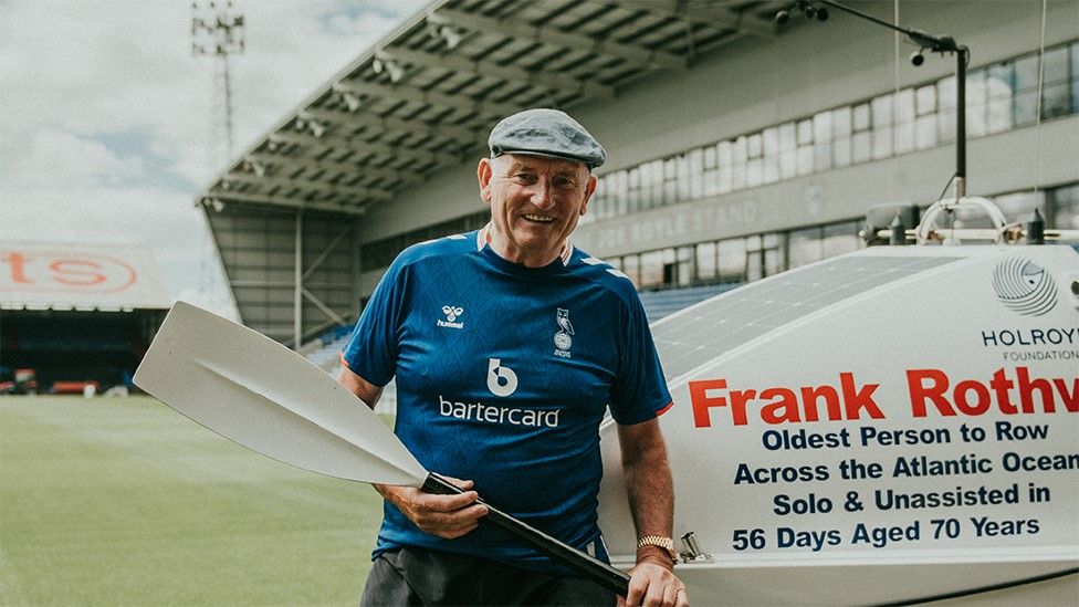Frank Rothwell holding an oar at Oldham Athletic's stadium