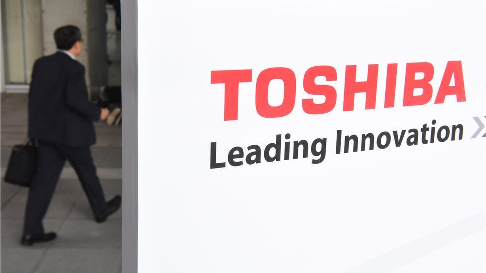Man walking past a Toshiba sign