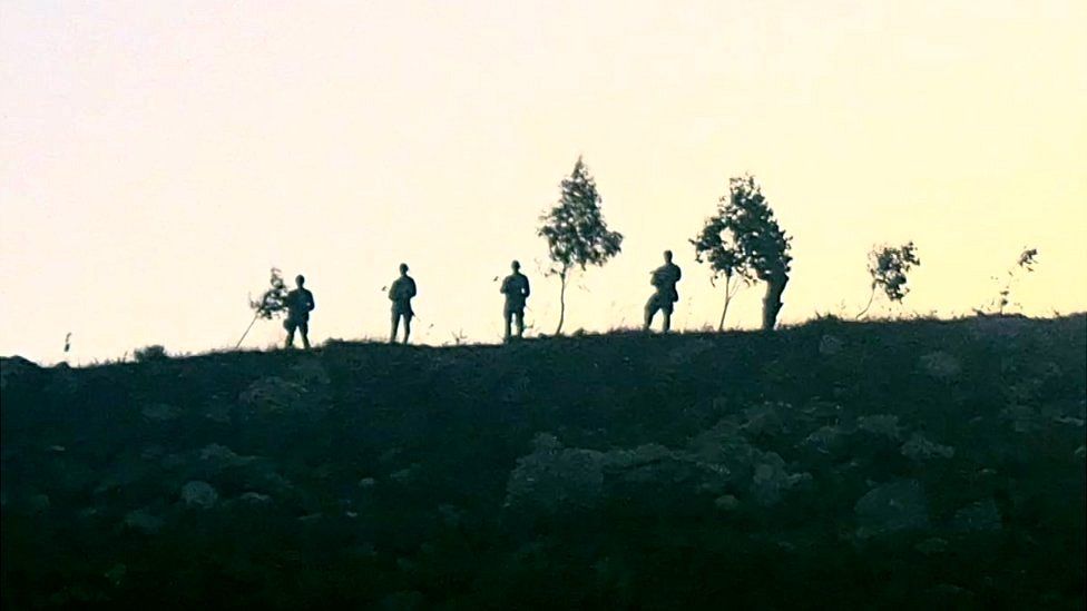 A video screenshot supplied by apple farmer Levav Weinberg shows armed men on a hill