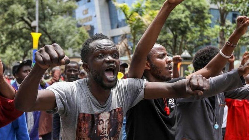 Kenyan small and medium enterprise traders hold placards and shout slogans during a protest against Chinese nationals owning businesses that engage in import, manufacture and distribution