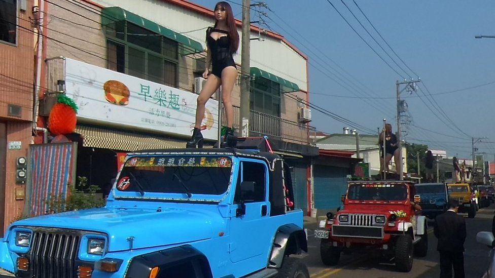 This picture taken on 3 January 2017 shows pole dancers performing on top of jeeps during the funeral procession of former Chiayi City county council speaker Tung Hsiang in Chiayi City, southern Taiwan