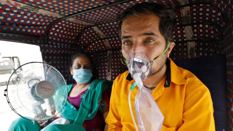 Patient in an oxygen mask waiting to enter hospital in Ahmedabad, India