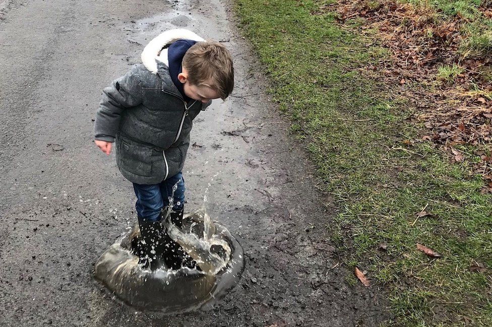 Boy jumping in a hole filled with water