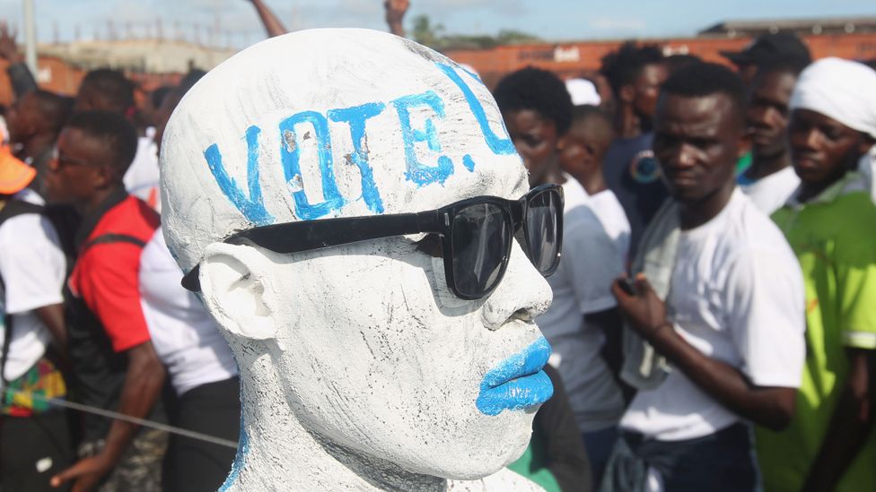 A man in Liberia wearing face paint and sunglasses with "vote" written on his forehead - 1 October 2023
