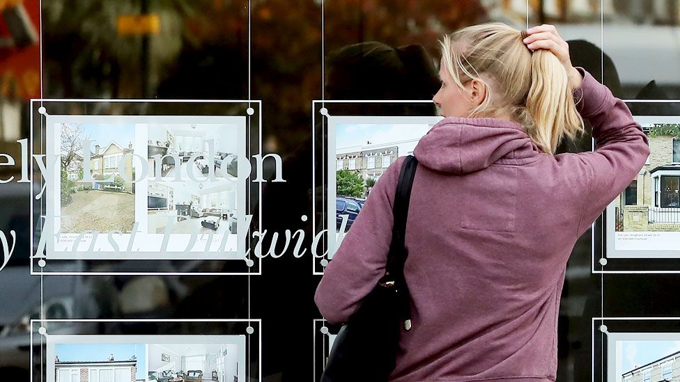 Woman looking at estate agents window