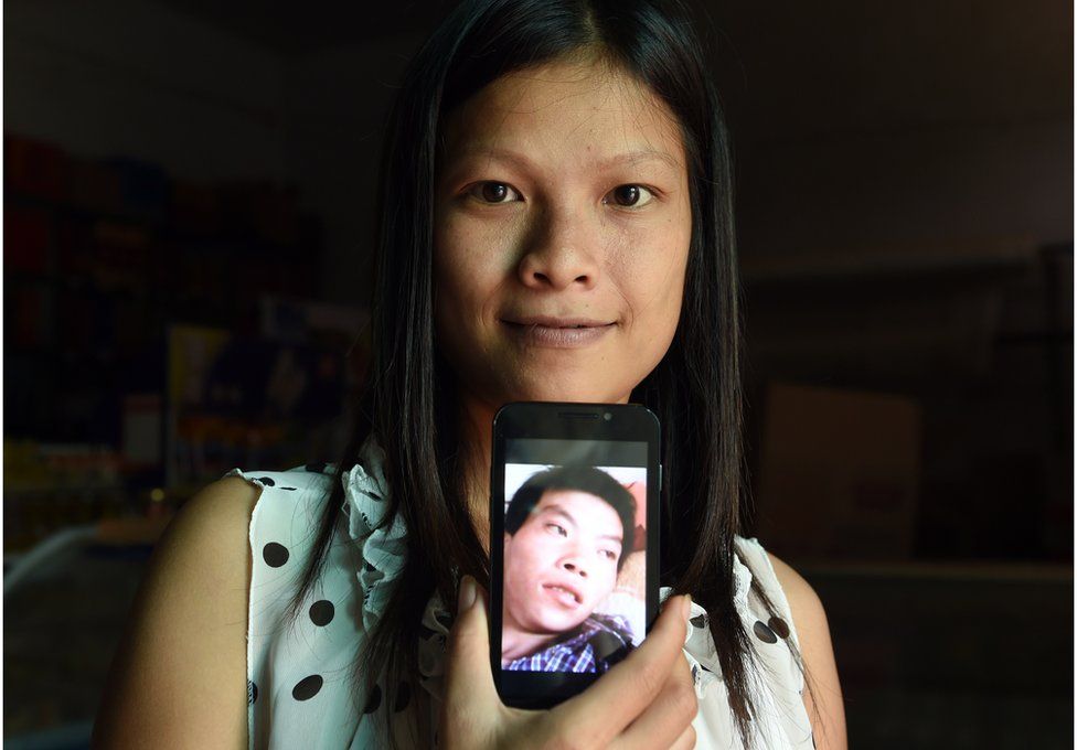 This photo taken on 30 July 2014 shows shows 21-year-old Vietnamese bride Vu Thi Hong Thuy posing with a photo of her Chinese husband in Weijian village, in China's Henan province.