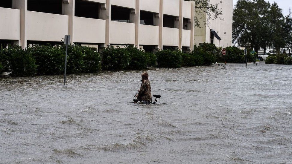 Мужчина идет на велосипеде по улице, затопленной ураганом Салли, в Пенсаколе, Флорида, 16 сентября 2020 г.