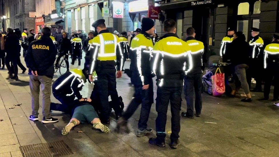 Irish police detain a man on O'Connell Street the night after serious disorder broke out in Dublin