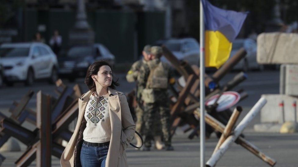 A woman walks in front of a Ukrainian flag in Kyiv