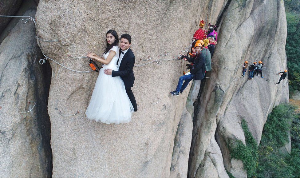A wedding photo shoot on a cliff face with the couple in formal wear.