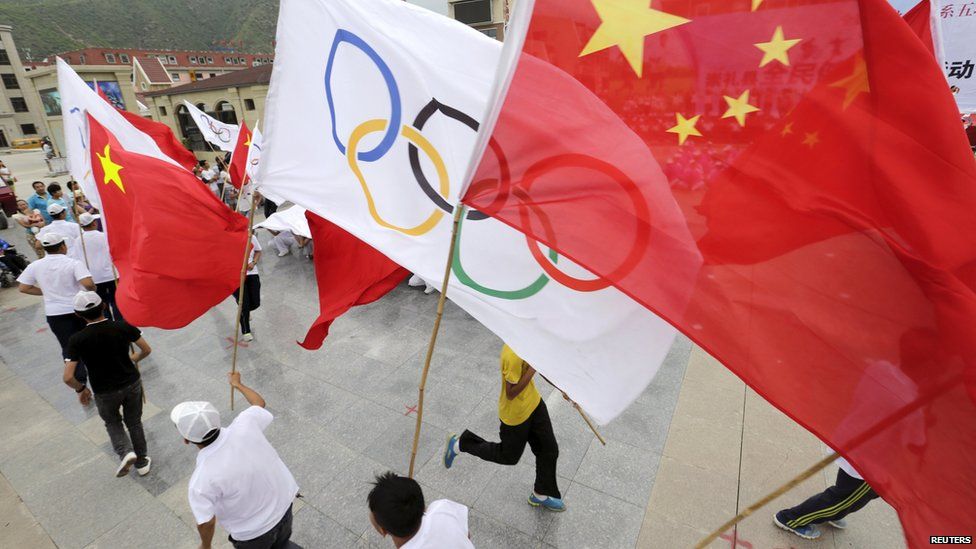 Local residents holding Chinese and Olympics flags attend a rehearsal for a possible upcoming celebration event on Friday afternoon, at a square in Chongli county of Zhangjiakou,
