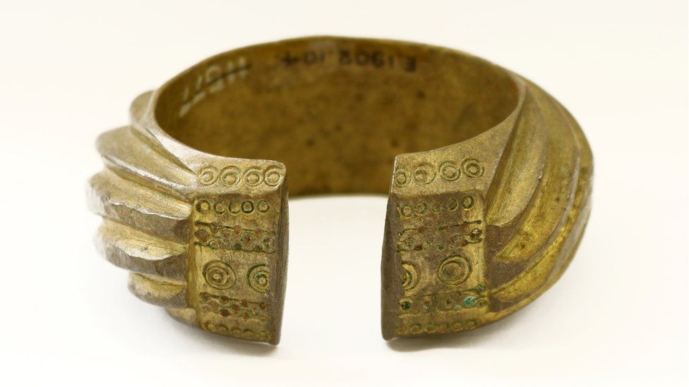 A brass penannular bracelet decorated with heavy slanting bands