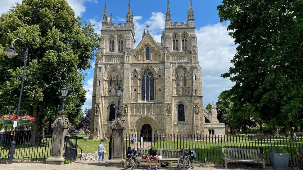 Cyclists on a tour across the UK take a break in the sunshine outside Selby Abbey