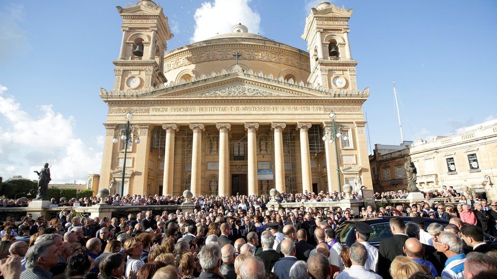People attend a ceremony as a coffin of journalist Daphne Caruana Galizia, who was murdered in a car bomb attack, leaves the Rotunda Parish Church in Mosta