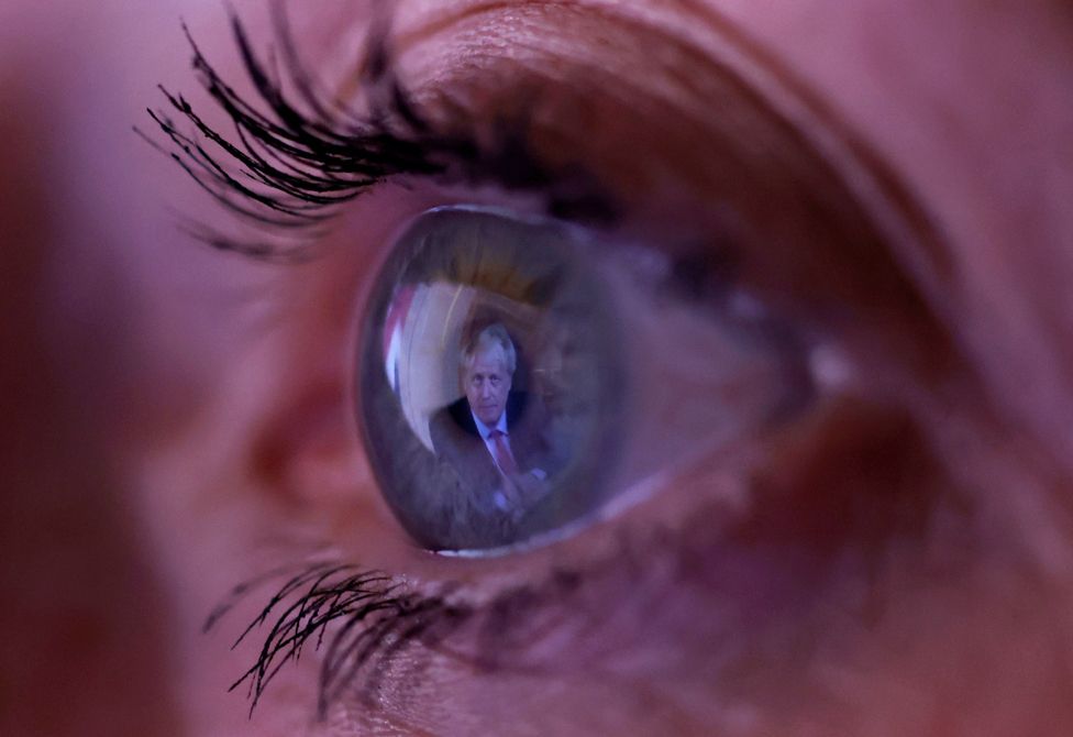 A close up of a woman's eye with the image of Boris Johnson reflected in her iris