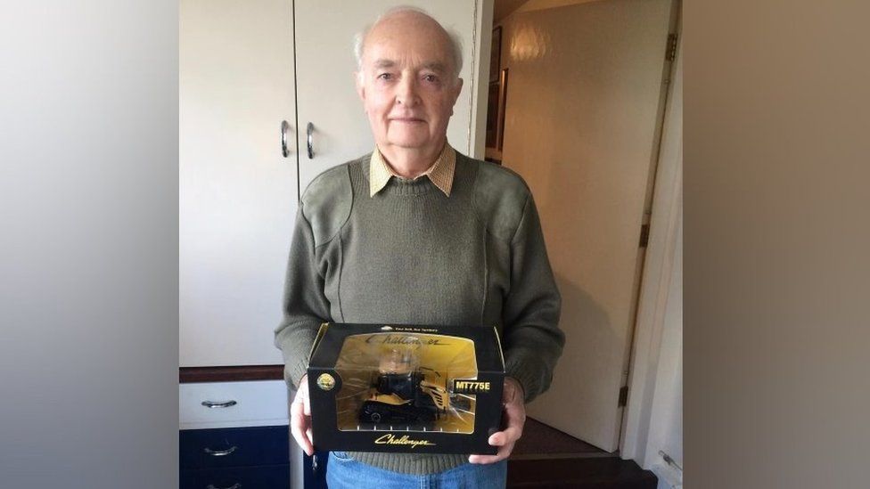 Jim Russell holding tractor memorabilia