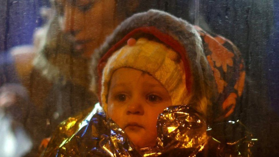 A refugee child looking out through the window of a bus in Poland