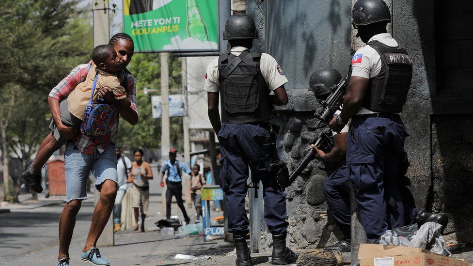 A man carries his son as they look for cover after leaving school amid gang violence in Port-au-Prince, Haiti March 3, 2023.