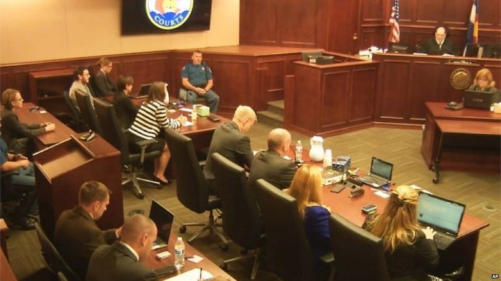 James Holmes (top left in a tan shirt) watches as Judge Carlos Samour (top right) prepares to reveal the jury's decision