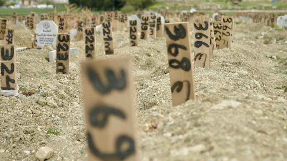 Ряды безымянных могил с самодельными пронумерованными указателями, где захоронены жертвы землетрясения