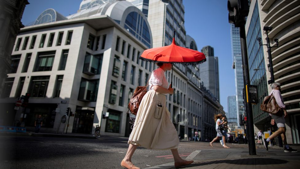 A woman walks through the city of London with an umbrella