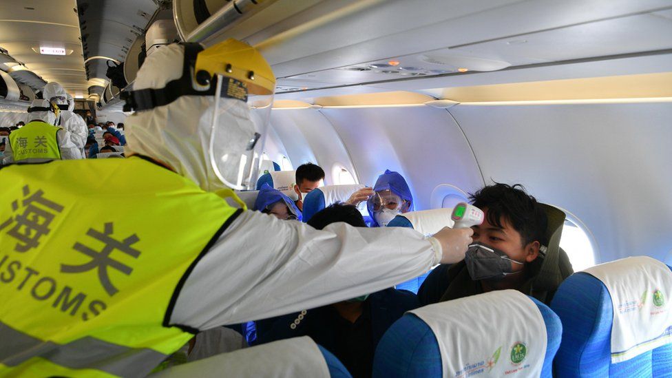 Сотрудник таможни проверяет температуру на борту самолета после приземления в Китае