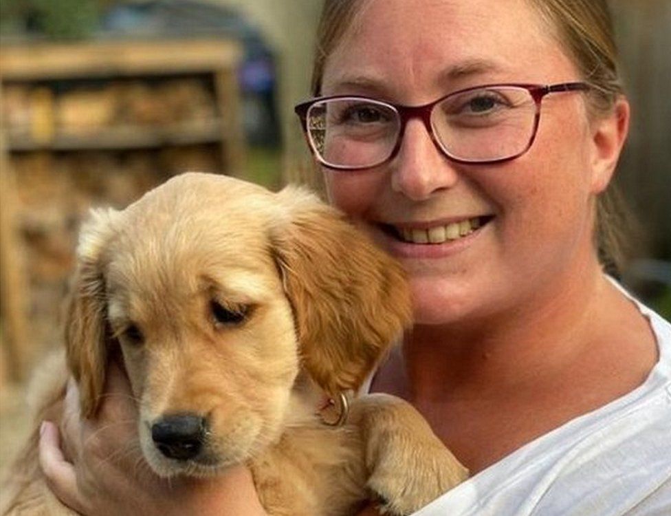 Ms Riley holding a Golden Retriever puppy.