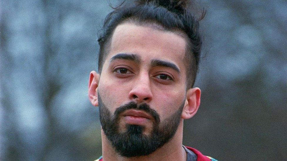 Adil Malik, a bearded Asian man looking at the camera with a slightly tilted head. The background outdoors and is blurred.