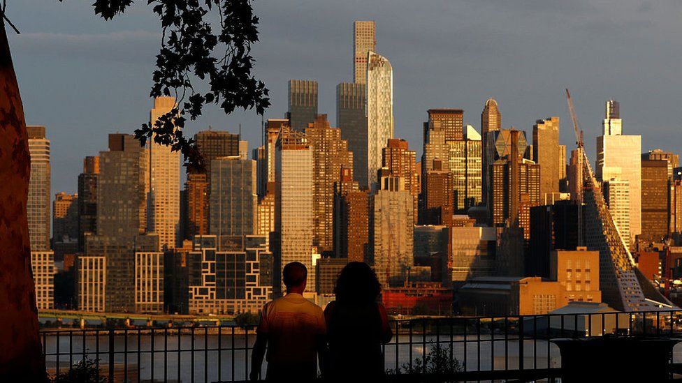 People in West New York, New Jersey watch the sun set on New York, August 23, 2015.