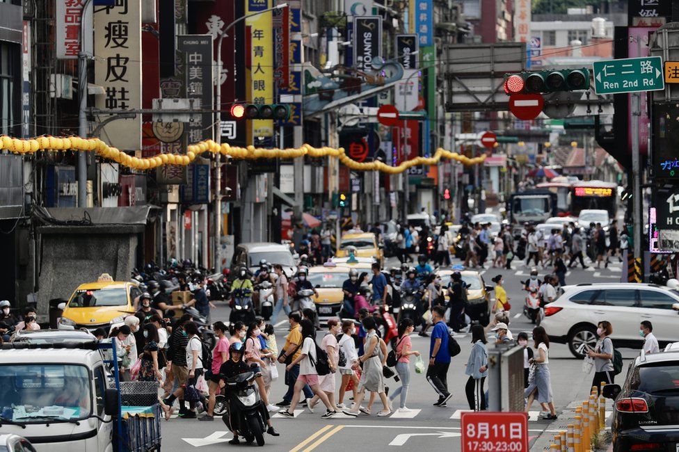 People cross a busy street in Keelung city, Taiwan, 05 August 2022.