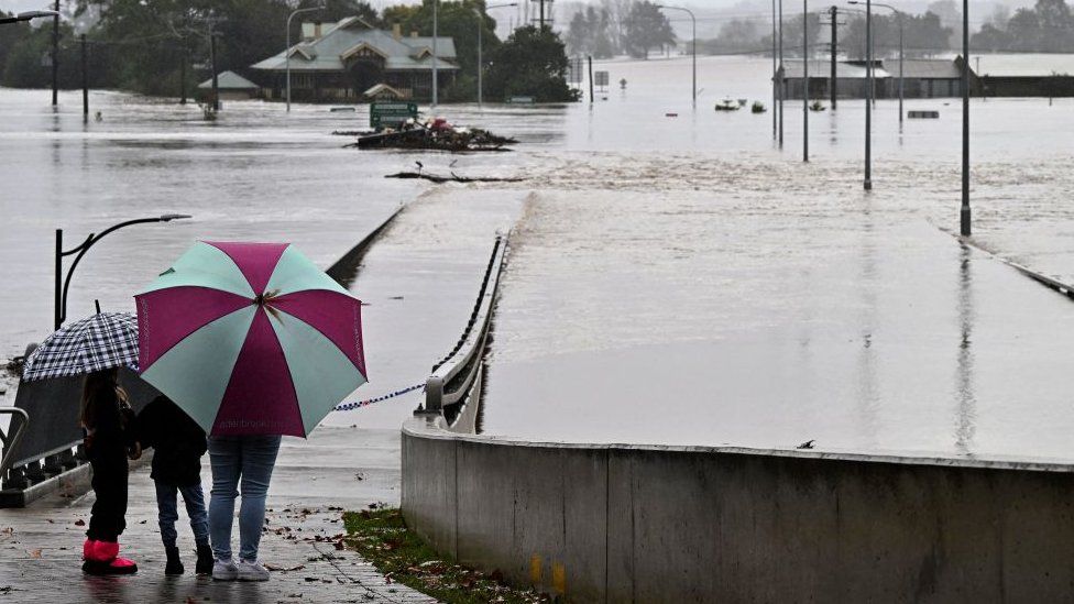 Two people observe a flooded bridge