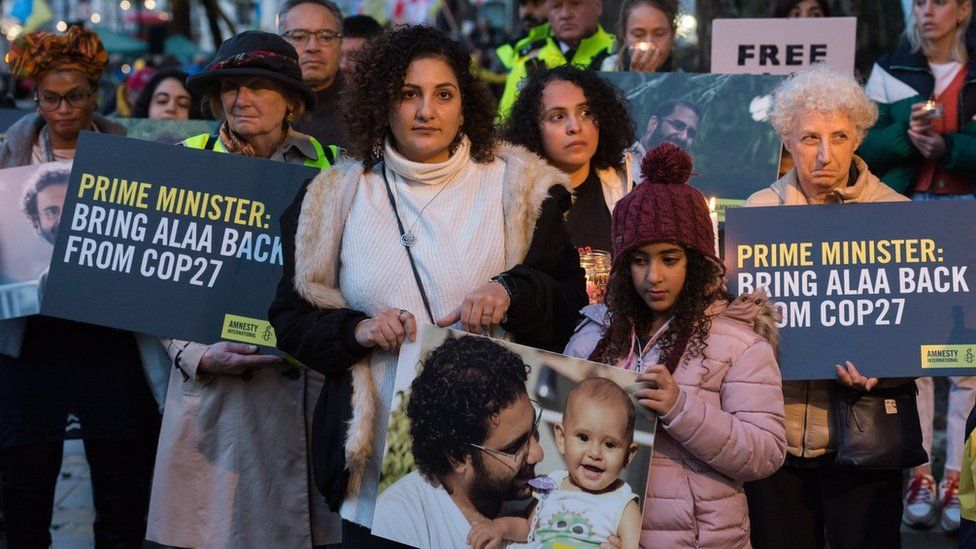 The sister of jailed British-Egyptian activist Alaa Abdel Fattah, Mona Seif (C) attends a nigh-time vigil in London to call on the British prime minister to secure his release at the COP27 summit (6 November 2022)