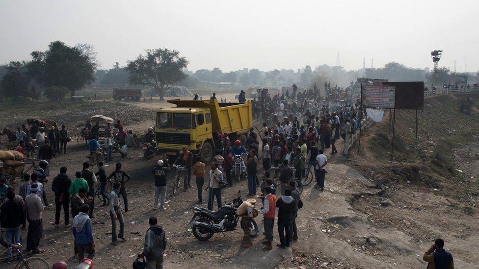 Bystanders look on as cargo trucks pass through the India-Nepal border at Birgunj on Friday