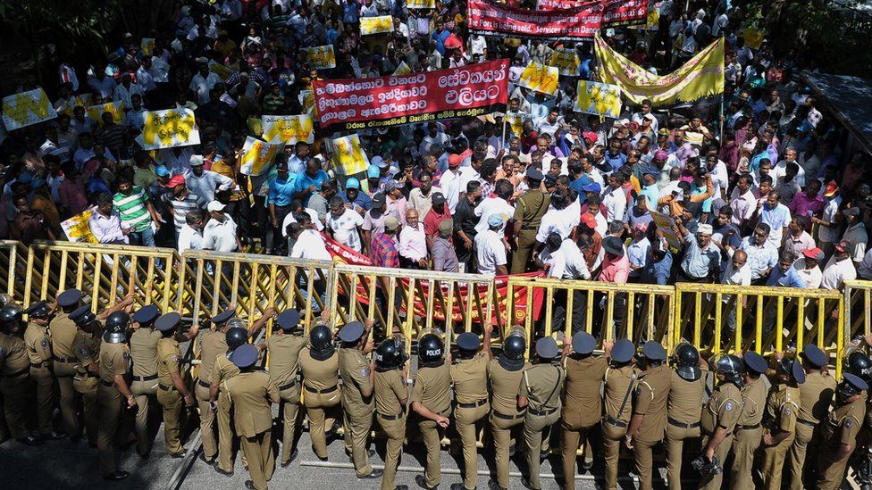 Sri Lankan police stand guard during a protest against the proposed sale of a stake in a loss-making port to a Chinese company in Colombo