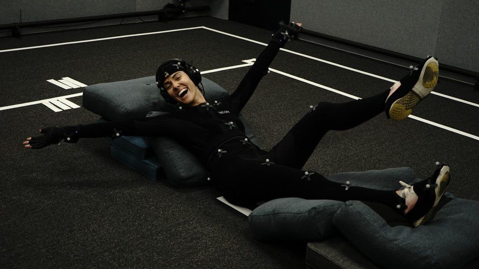 A woman wearing a motion capture suit. It's skin tight, with small, ping-pong style balls dotted around the surface. She's wearing over-ear headphones and laughing. She's on some cushions/crash mats on the floor. Her arms and legs are outstretched - she looks as if she's just landed after falling backwards.'s skin tight, with small, ping-pong style balls dotted around the surface. She's wearing over-ear headphones and laughing. She's on some cushions/crash mats on the floor. Her arms and legs are outstretched - she looks as if she's just landed after falling backwards.'s skin tight, with small, ping-pong style balls dotted around the surface. She's wearing over-ear headphones and laughing. She's on some cushions/crash mats on the floor. Her arms and legs are outstretched - she looks as if she's just landed after falling backwards.'s skin tight, with small, ping-pong style balls dotted around the surface. She's wearing over-ear headphones and laughing. She's on some cushions/crash mats on the floor. Her arms and legs are outstretched - she looks as if she's just landed after falling backwards.'s skin tight, with small, ping-pong style balls dotted around the surface. She's wearing over-ear headphones and laughing. She's on some cushions/crash mats on the floor. Her arms and legs are outstretched - she looks as if she's just landed after falling backwards.'s skin tight, with small, ping-pong style balls dotted around the surface. She's wearing over-ear headphones and laughing. She's on some cushions/crash mats on the floor. Her arms and legs are outstretched - she looks as if she's just landed after falling backwards.'s skin tight, with small, ping-pong style balls dotted around the surface. She's wearing over-ear headphones and laughing. She's on some cushions/crash mats on the floor. Her arms and legs are outstretched - she looks as if she's just landed after falling backwards.'s skin tight, with small, ping-pong style balls dotted around the surface. She's wearing over-ear headphones and laughing. She's on some cushions/crash mats on the floor. Her arms and legs are outstretched - she looks as if she's just landed after falling backwards.'s skin tight, with small, ping-pong style balls dotted around the surface. She's wearing over-ear headphones and laughing. She's on some cushions/crash mats on the floor. Her arms and legs are outstretched - she looks as if she's just landed after falling backwards.'s skin tight, with small, ping-pong style balls dotted around the surface. She's wearing over-ear headphones and laughing. She's on some cushions/crash mats on the floor. Her arms and legs are outstretched - she looks as if she's just landed after falling backwards.'s skin tight, with small, ping-pong style balls dotted around the surface. She's wearing over-ear headphones and laughing. She's on some cushions/crash mats on the floor. Her arms and legs are outstretched - she looks as if she's just landed after falling backwards.'s skin tight, with small, ping-pong style balls dotted around the surface. She's wearing over-ear headphones and laughing. She's on some cushions/crash mats on the floor. Her arms and legs are outstretched - she looks as if she's just landed after falling backwards.'s skin tight, with small, ping-pong style balls dotted around the surface. She's wearing over-ear headphones and laughing. She's on some cushions/crash mats on the floor. Her arms and legs are outstretched - she looks as if she's just landed after falling backwards.'s skin tight, with small, ping-pong style balls dotted around the surface. She's wearing over-ear headphones and laughing. She's on some cushions/crash mats on the floor. Her arms and legs are outstretched - she looks as if she's just landed after falling backwards.'s skin tight, with small, ping-pong style balls dotted around the surface. She's wearing over-ear headphones and laughing. She's on some cushions/crash mats on the floor. Her arms and legs are outstretched - she looks as if she's just landed after falling backwards.'s skin tight, with small, ping-pong style balls dotted around the surface. She's wearing over-ear headphones and laughing. She's on some cushions/crash mats on the floor. Her arms and legs are outstretched - she looks as if she's just landed after falling backwards.'s skin tight, with small, ping-pong style balls dotted around the surface. She's wearing over-ear headphones and laughing. She's on some cushions/crash mats on the floor. Her arms and legs are outstretched - she looks as if she's just landed after falling backwards.'s skin tight, with small, ping-pong style balls dotted around the surface. She's wearing over-ear headphones and laughing. She's on some cushions/crash mats on the floor. Her arms and legs are outstretched - she looks as if she's just landed after falling backwards.'s skin tight, with small, ping-pong style balls dotted around the surface. She's wearing over-ear headphones and laughing. She's on some cushions/crash mats on the floor. Her arms and legs are outstretched - she looks as if she's just landed after falling backwards.'s skin tight, with small, ping-pong style balls dotted around the surface. She's wearing over-ear headphones and laughing. She's on some cushions/crash mats on the floor. Her arms and legs are outstretched - she looks as if she's just landed after falling backwards.'s skin tight, with small, ping-pong style balls dotted around the surface. She's wearing over-ear headphones and laughing. She's on some cushions/crash mats on the floor. Her arms and legs are outstretched - she looks as if she's just landed after falling backwards.'s skin tight, with small, ping-pong style balls dotted around the surface. She's wearing over-ear headphones and laughing. She's on some cushions/crash mats on the floor. Her arms and legs are outstretched - she looks as if she's just landed after falling backwards.'s skin tight, with small, ping-pong style balls dotted around the surface. She's wearing over-ear headphones and laughing. She's on some cushions/crash mats on the floor. Her arms and legs are outstretched - she looks as if she's just landed after falling backwards.'s skin tight, with small, ping-pong style balls dotted around the surface. She's wearing over-ear headphones and laughing. She's on some cushions/crash mats on the floor. Her arms and legs are outstretched - she looks as if she's just landed after falling backwards.'s skin tight, with small, ping-pong style balls dotted around the surface. She's wearing over-ear headphones and laughing. She's on some cushions/crash mats on the floor. Her arms and legs are outstretched - she looks as if she's just landed after falling backwards.'s skin tight, with small, ping-pong style balls dotted around the surface. She's wearing over-ear headphones and laughing. She's on some cushions/crash mats on the floor. Her arms and legs are outstretched - she looks as if she's just landed after falling backwards.'s skin tight, with small, ping-pong style balls dotted around the surface. She's wearing over-ear headphones and laughing. She's on some cushions/crash mats on the floor. Her arms and legs are outstretched - she looks as if she's just landed after falling backwards.'s skin tight, with small, ping-pong style balls dotted around the surface. She's wearing over-ear headphones and laughing. She's on some cushions/crash mats on the floor. Her arms and legs are outstretched - she looks as if she's just landed after falling backwards.'s skin tight, with small, ping-pong style balls dotted around the surface. She's wearing over-ear headphones and laughing. She's on some cushions/crash mats on the floor. Her arms and legs are outstretched - she looks as if she's just landed after falling backwards.'s skin tight, with small, ping-pong style balls dotted around the surface. She's wearing over-ear headphones and laughing. She's on some cushions/crash mats on the floor. Her arms and legs are outstretched - she looks as if she's just landed after falling backwards.'s skin tight, with small, ping-pong style balls dotted around the surface. She's wearing over-ear headphones and laughing. She's on some cushions/crash mats on the floor. Her arms and legs are outstretched - she looks as if she's just landed after falling backwards.'s skin tight, with small, ping-pong style balls dotted around the surface. She's wearing over-ear headphones and laughing. She's on some cushions/crash mats on the floor. Her arms and legs are outstretched - she looks as if she's just landed after falling backwards.'s skin tight, with small, ping-pong style balls dotted around the surface. She's wearing over-ear headphones and laughing. She's on some cushions/crash mats on the floor. Her arms and legs are outstretched - she looks as if she's just landed after falling backwards.'s skin tight, with small, ping-pong style balls dotted around the surface. She's wearing over-ear headphones and laughing. She's on some cushions/crash mats on the floor. Her arms and legs are outstretched - she looks as if she's just landed after falling backwards.'s skin tight, with small, ping-pong style balls dotted around the surface. She's wearing over-ear headphones and laughing. She's on some cushions/crash mats on the floor. Her arms and legs are outstretched - she looks as if she's just landed after falling backwards.'s skin tight, with small, ping-pong style balls dotted around the surface. She's wearing over-ear headphones and laughing. She's on some cushions/crash mats on the floor. Her arms and legs are outstretched - she looks as if she's just landed after falling backwards.'s skin tight, with small, ping-pong style balls dotted around the surface. She's wearing over-ear headphones and laughing. She's on some cushions/crash mats on the floor. Her arms and legs are outstretched - she looks as if she's just landed after falling backwards.'s skin tight, with small, ping-pong style balls dotted around the surface. She's wearing over-ear headphones and laughing. She's on some cushions/crash mats on the floor. Her arms and legs are outstretched - she looks as if she's just landed after falling backwards.'s skin tight, with small, ping-pong style balls dotted around the surface. She's wearing over-ear headphones and laughing. She's on some cushions/crash mats on the floor. Her arms and legs are outstretched - she looks as if she's just landed after falling backwards.'s skin tight, with small, ping-pong style balls dotted around the surface. She's wearing over-ear headphones and laughing. She's on some cushions/crash mats on the floor. Her arms and legs are outstretched - she looks as if she's just landed after falling backwards.'s skin tight, with small, ping-pong style balls dotted around the surface. She's wearing over-ear headphones and laughing. She's on some cushions/crash mats on the floor. Her arms and legs are outstretched - she looks as if she's just landed after falling backwards.'s skin tight, with small, ping-pong style balls dotted around the surface. She's wearing over-ear headphones and laughing. She's on some cushions/crash mats on the floor. Her arms and legs are outstretched - she looks as if she's just landed after falling backwards.'s skin tight, with small, ping-pong style balls dotted around the surface. She's wearing over-ear headphones and laughing. She's on some cushions/crash mats on the floor. Her arms and legs are outstretched - she looks as if she's just landed after falling backwards.'s skin tight, with small, ping-pong style balls dotted around the surface. She's wearing over-ear headphones and laughing. She's on some cushions/crash mats on the floor. Her arms and legs are outstretched - she looks as if she's just landed after falling backwards.'s skin tight, with small, ping-pong style balls dotted around the surface. She's wearing over-ear headphones and laughing. She's on some cushions/crash mats on the floor. Her arms and legs are outstretched - she looks as if she's just landed after falling backwards.'s skin tight, with small, ping-pong style balls dotted around the surface. She's wearing over-ear headphones and laughing. She's on some cushions/crash mats on the floor. Her arms and legs are outstretched - she looks as if she's just landed after falling backwards.'s skin tight, with small, ping-pong style balls dotted around the surface. She's wearing over-ear headphones and laughing. She's on some cushions/crash mats on the floor. Her arms and legs are outstretched - she looks as if she's just landed after falling backwards.'s skin tight, with small, ping-pong style balls dotted around the surface. She's wearing over-ear headphones and laughing. She's on some cushions/crash mats on the floor. Her arms and legs are outstretched - she looks as if she's just landed after falling backwards.'s skin tight, with small, ping-pong style balls dotted around the surface. She's wearing over-ear headphones and laughing. She's on some cushions/crash mats on the floor. Her arms and legs are outstretched - she looks as if she's just landed after falling backwards.'s skin tight, with small, ping-pong style balls dotted around the surface. She's wearing over-ear headphones and laughing. She's on some cushions/crash mats on the floor. Her arms and legs are outstretched - she looks as if she's just landed after falling backwards.'s skin tight, with small, ping-pong style balls dotted around the surface. She's wearing over-ear headphones and laughing. She's on some cushions/crash mats on the floor. Her arms and legs are outstretched - she looks as if she's just landed after falling backwards.'s skin tight, with small, ping-pong style balls dotted around the surface. She's wearing over-ear headphones and laughing. She's on some cushions/crash mats on the floor. Her arms and legs are outstretched - she looks as if she's just landed after falling backwards.'s skin tight, with small, ping-pong style balls dotted around the surface. She's wearing over-ear headphones and laughing. She's on some cushions/crash mats on the floor. Her arms and legs are outstretched - she looks as if she's just landed after falling backwards.'s skin tight, with small, ping-pong style balls dotted around the surface. She's wearing over-ear headphones and laughing. She's on some cushions/crash mats on the floor. Her arms and legs are outstretched - she looks as if she's just landed after falling backwards.'s skin tight, with small, ping-pong style balls dotted around the surface. She's wearing over-ear headphones and laughing. She's on some cushions/crash mats on the floor. Her arms and legs are outstretched - she looks as if she's just landed after falling backwards.'s skin tight, with small, ping-pong style balls dotted around the surface. She's wearing over-ear headphones and laughing. She's on some cushions/crash mats on the floor. Her arms and legs are outstretched - she looks as if she's just landed after falling backwards.'s skin tight, with small, ping-pong style balls dotted around the surface. She's wearing over-ear headphones and laughing. She's on some cushions/crash mats on the floor. Her arms and legs are outstretched - she looks as if she's just landed after falling backwards.'s skin tight, with small, ping-pong style balls dotted around the surface. She's wearing over-ear headphones and laughing. She's on some cushions/crash mats on the floor. Her arms and legs are outstretched - she looks as if she's just landed after falling backwards.'s skin tight, with small, ping-pong style balls dotted around the surface. She's wearing over-ear headphones and laughing. She's on some cushions/crash mats on the floor. Her arms and legs are outstretched - she looks as if she's just landed after falling backwards.'s skin tight, with small, ping-pong style balls dotted around the surface. She's wearing over-ear headphones and laughing. She's on some cushions/crash mats on the floor. Her arms and legs are outstretched - she looks as if she's just landed after falling backwards.'s skin tight, with small, ping-pong style balls dotted around the surface. She's wearing over-ear headphones and laughing. She's on some cushions/crash mats on the floor. Her arms and legs are outstretched - she looks as if she's just landed after falling backwards.'s skin tight, with small, ping-pong style balls dotted around the surface. She's wearing over-ear headphones and laughing. She's on some cushions/crash mats on the floor. Her arms and legs are outstretched - she looks as if she's just landed after falling backwards.'s skin tight, with small, ping-pong style balls dotted around the surface. She's wearing over-ear headphones and laughing. She's on some cushions/crash mats on the floor. Her arms and legs are outstretched - she looks as if she's just landed after falling backwards.'s skin tight, with small, ping-pong style balls dotted around the surface. She's wearing over-ear headphones and laughing. She's on some cushions/crash mats on the floor. Her arms and legs are outstretched - she looks as if she's just landed after falling backwards.'s skin tight, with small, ping-pong style balls dotted around the surface. She's wearing over-ear headphones and laughing. She's on some cushions/crash mats on the floor. Her arms and legs are outstretched - she looks as if she's just landed after falling backwards.'s skin tight, with small, ping-pong style balls dotted around the surface. She's wearing over-ear headphones and laughing. She's on some cushions/crash mats on the floor. Her arms and legs are outstretched - she looks as if she's just landed after falling backwards.'s skin tight, with small, ping-pong style balls dotted around the surface. She's wearing over-ear headphones and laughing. She's on some cushions/crash mats on the floor. Her arms and legs are outstretched - she looks as if she's just landed after falling backwards.'s skin tight, with small, ping-pong style balls dotted around the surface. She's wearing over-ear headphones and laughing. She's on some cushions/crash mats on the floor. Her arms and legs are outstretched - she looks as if she's just landed after falling backwards.'s skin tight, with small, ping-pong style balls dotted around the surface. She's wearing over-ear headphones and laughing. She's on some cushions/crash mats on the floor. Her arms and legs are outstretched - she looks as if she's just landed after falling backwards.'s skin tight, with small, ping-pong style balls dotted around the surface. She's wearing over-ear headphones and laughing. She's on some cushions/crash mats on the floor. Her arms and legs are outstretched - she looks as if she's just landed after falling backwards.'s skin tight, with small, ping-pong style balls dotted around the surface. She's wearing over-ear headphones and laughing. She's on some cushions/crash mats on the floor. Her arms and legs are outstretched - she looks as if she's just landed after falling backwards.'s skin tight, with small, ping-pong style balls dotted around the surface. She's wearing over-ear headphones and laughing. She's on some cushions/crash mats on the floor. Her arms and legs are outstretched - she looks as if she's just landed after falling backwards.'s skin tight, with small, ping-pong style balls dotted around the surface. She's wearing over-ear headphones and laughing. She's on some cushions/crash mats on the floor. Her arms and legs are outstretched - she looks as if she's just landed after falling backwards.'s skin tight, with small, ping-pong style balls dotted around the surface. She's wearing over-ear headphones and laughing. She's on some cushions/crash mats on the floor. Her arms and legs are outstretched - she looks as if she's just landed after falling backwards.'s skin tight, with small, ping-pong style balls dotted around the surface. She's wearing over-ear headphones and laughing. She's on some cushions/crash mats on the floor. Her arms and legs are outstretched - she looks as if she's just landed after falling backwards.'s skin tight, with small, ping-pong style balls dotted around the surface. She's wearing over-ear headphones and laughing. She's on some cushions/crash mats on the floor. Her arms and legs are outstretched - she looks as if she's just landed after falling backwards.'s skin tight, with small, ping-pong style balls dotted around the surface. She's wearing over-ear headphones and laughing. She's on some cushions/crash mats on the floor. Her arms and legs are outstretched - she looks as if she's just landed after falling backwards.'s skin tight, with small, ping-pong style balls dotted around the surface. She's wearing over-ear headphones and laughing. She's on some cushions/crash mats on the floor. Her arms and legs are outstretched - she looks as if she's just landed after falling backwards.'s skin tight, with small, ping-pong style balls dotted around the surface. She's wearing over-ear headphones and laughing. She's on some cushions/crash mats on the floor. Her arms and legs are outstretched - she looks as if she's just landed after falling backwards.'s skin tight, with small, ping-pong style balls dotted around the surface. She's wearing over-ear headphones and laughing. She's on some cushions/crash mats on the floor. Her arms and legs are outstretched - she looks as if she's just landed after falling backwards.'s skin tight, with small, ping-pong style balls dotted around the surface. She's wearing over-ear headphones and laughing. She's on some cushions/crash mats on the floor. Her arms and legs are outstretched - she looks as if she's just landed after falling backwards.'s skin tight, with small, ping-pong style balls dotted around the surface. She's wearing over-ear headphones and laughing. She's on some cushions/crash mats on the floor. Her arms and legs are outstretched - she looks as if she's just landed after falling backwards.'s skin tight, with small, ping-pong style balls dotted around the surface. She's wearing over-ear headphones and laughing. She's on some cushions/crash mats on the floor. Her arms and legs are outstretched - she looks as if she's just landed after falling backwards.'s skin tight, with small, ping-pong style balls dotted around the surface. She's wearing over-ear headphones and laughing. She's on some cushions/crash mats on the floor. Her arms and legs are outstretched - she looks as if she's just landed after falling backwards.'s skin tight, with small, ping-pong style balls dotted around the surface. She's wearing over-ear headphones and laughing. She's on some cushions/crash mats on the floor. Her arms and legs are outstretched - she looks as if she's just landed after falling backwards.'s skin tight, with small, ping-pong style balls dotted around the surface. She's wearing over-ear headphones and laughing. She's on some cushions/crash mats on the floor. Her arms and legs are outstretched - she looks as if she's just landed after falling backwards.'s skin tight, with small, ping-pong style balls dotted around the surface. She's wearing over-ear headphones and laughing. She's on some cushions/crash mats on the floor. Her arms and legs are outstretched - she looks as if she's just landed after falling backwards.'s skin tight, with small, ping-pong style balls dotted around the surface. She's wearing over-ear headphones and laughing. She's on some cushions/crash mats on the floor. Her arms and legs are outstretched - she looks as if she's just landed after falling backwards.'s skin tight, with small, ping-pong style balls dotted around the surface. She's wearing over-ear headphones and laughing. She's on some cushions/crash mats on the floor. Her arms and legs are outstretched - she looks as if she's just landed after falling backwards.'s skin tight, with small, ping-pong style balls dotted around the surface. She's wearing over-ear headphones and laughing. She's on some cushions/crash mats on the floor. Her arms and legs are outstretched - she looks as if she's just landed after falling backwards.'s skin tight, with small, ping-pong style balls dotted around the surface. She's wearing over-ear headphones and laughing. She's on some cushions/crash mats on the floor. Her arms and legs are outstretched - she looks as if she's just landed after falling backwards.'s skin tight, with small, ping-pong style balls dotted around the surface. She's wearing over-ear headphones and laughing. She's on some cushions/crash mats on the floor. Her arms and legs are outstretched - she looks as if she's just landed after falling backwards.'s skin tight, with small, ping-pong style balls dotted around the surface. She's wearing over-ear headphones and laughing. She's on some cushions/crash mats on the floor. Her arms and legs are outstretched - she looks as if she's just landed after falling backwards.'s skin tight, with small, ping-pong style balls dotted around the surface. She's wearing over-ear headphones and laughing. She's on some cushions/crash mats on the floor. Her arms and legs are outstretched - she looks as if she's just landed after falling backwards.'s skin tight, with small, ping-pong style balls dotted around the surface. She's wearing over-ear headphones and laughing. She's on some cushions/crash mats on the floor. Her arms and legs are outstretched - she looks as if she's just landed after falling backwards.'s skin tight, with small, ping-pong style balls dotted around the surface. She's wearing over-ear headphones and laughing. She's on some cushions/crash mats on the floor. Her arms and legs are outstretched - she looks as if she's just landed after falling backwards.'s skin tight, with small, ping-pong style balls dotted around the surface. She's wearing over-ear headphones and laughing. She's on some cushions/crash mats on the floor. Her arms and legs are outstretched - she looks as if she's just landed after falling backwards.'s skin tight, with small, ping-pong style balls dotted around the surface. She's wearing over-ear headphones and laughing. She's on some cushions/crash mats on the floor. Her arms and legs are outstretched - she looks as if she's just landed after falling backwards.'s skin tight, with small, ping-pong style balls dotted around the surface. She's wearing over-ear headphones and laughing. She's on some cushions/crash mats on the floor. Her arms and legs are outstretched - she looks as if she's just landed after falling backwards.'s skin tight, with small, ping-pong style balls dotted around the surface. She's wearing over-ear headphones and laughing. She's on some cushions/crash mats on the floor. Her arms and legs are outstretched - she looks as if she's just landed after falling backwards.'s skin tight, with small, ping-pong style balls dotted around the surface. She's wearing over-ear headphones and laughing. She's on some cushions/crash mats on the floor. Her arms and legs are outstretched - she looks as if she's just landed after falling backwards.'s skin tight, with small, ping-pong style balls dotted around the surface. She's wearing over-ear headphones and laughing. She's on some cushions/crash mats on the floor. Her arms and legs are outstretched - she looks as if she's just landed after falling backwards.'s skin tight, with small, ping-pong style balls dotted around the surface. She's wearing over-ear headphones and laughing. She's on some cushions/crash mats on the floor. Her arms and legs are outstretched - she looks as if she's just landed after falling backwards.'s skin tight, with small, ping-pong style balls dotted around the surface. She's wearing over-ear headphones and laughing. She's on some cushions/crash mats on the floor. Her arms and legs are outstretched - she looks as if she's just landed after falling backwards.'s skin tight, with small, ping-pong style balls dotted around the surface. She's wearing over-ear headphones and laughing. She's on some cushions/crash mats on the floor. Her arms and legs are outstretched - she looks as if she's just landed after falling backwards.'s skin tight, with small, ping-pong style balls dotted around the surface. She's wearing over-ear headphones and laughing. She's on some cushions/crash mats on the floor. Her arms and legs are outstretched - she looks as if she's just landed after falling backwards.'s skin tight, with small, ping-pong style balls dotted around the surface. She's wearing over-ear headphones and laughing. She's on some cushions/crash mats on the floor. Her arms and legs are outstretched - she looks as if she's just landed after falling backwards.'s skin tight, with small, ping-pong style balls dotted around the surface. She's wearing over-ear headphones and laughing. She's on some cushions/crash mats on the floor. Her arms and legs are outstretched - she looks as if she's just landed after falling backwards.'s skin tight, with small, ping-pong style balls dotted around the surface. She's wearing over-ear headphones and laughing. She's on some cushions/crash mats on the floor. Her arms and legs are outstretched - she looks as if she's just landed after falling backwards.'s skin tight, with small, ping-pong style balls dotted around the surface. She's wearing over-ear headphones and laughing. She's on some cushions/crash mats on the floor. Her arms and legs are outstretched - she looks as if she's just landed after falling backwards.'s skin tight, with small, ping-pong style balls dotted around the surface. She's wearing over-ear headphones and laughing. She's on some cushions/crash mats on the floor. Her arms and legs are outstretched - she looks as if she's just landed after falling backwards.'s skin tight, with small, ping-pong style balls dotted around the surface. She's wearing over-ear headphones and laughing. She's on some cushions/crash mats on the floor. Her arms and legs are outstretched - she looks as if she's just landed after falling backwards.'s skin tight, with small, ping-pong style balls dotted around the surface. She's wearing over-ear headphones and laughing. She's on some cushions/crash mats on the floor. Her arms and legs are outstretched - she looks as if she's just landed after falling backwards.'s skin tight, with small, ping-pong style balls dotted around the surface. She's wearing over-ear headphones and laughing. She's on some cushions/crash mats on the floor. Her arms and legs are outstretched - she looks as if she's just landed after falling backwards.'s skin tight, with small, ping-pong style balls dotted around the surface. She's wearing over-ear headphones and laughing. She's on some cushions/crash mats on the floor. Her arms and legs are outstretched - she looks as if she's just landed after falling backwards.'s skin tight, with small, ping-pong style balls dotted around the surface. She's wearing over-ear headphones and laughing. She's on some cushions/crash mats on the floor. Her arms and legs are outstretched - she looks as if she's just landed after falling backwards.'s skin tight, with small, ping-pong style balls dotted around the surface. She's wearing over-ear headphones and laughing. She's on some cushions/crash mats on the floor. Her arms and legs are outstretched - she looks as if she's just landed after falling backwards.'s skin tight, with small, ping-pong style balls dotted around the surface. She's wearing over-ear headphones and laughing. She's on some cushions/crash mats on the floor. Her arms and legs are outstretched - she looks as if she's just landed after falling backwards.'s skin tight, with small, ping-pong style balls dotted around the surface. She's wearing over-ear headphones and laughing. She's on some cushions/crash mats on the floor. Her arms and legs are outstretched - she looks as if she's just landed after falling backwards.'s skin tight, with small, ping-pong style balls dotted around the surface. She's wearing over-ear headphones and laughing. She's on some cushions/crash mats on the floor. Her arms and legs are outstretched - she looks as if she's just landed after falling backwards.'s skin tight, with small, ping-pong style balls dotted around the surface. She's wearing over-ear headphones and laughing. She's on some cushions/crash mats on the floor. Her arms and legs are outstretched - she looks as if she's just landed after falling backwards.'s skin tight, with small, ping-pong style balls dotted around the surface. She's wearing over-ear headphones and laughing. She's on some cushions/crash mats on the floor. Her arms and legs are outstretched - she looks as if she's just landed after falling backwards.'s skin tight, with small, ping-pong style balls dotted around the surface. She's wearing over-ear headphones and laughing. She's on some cushions/crash mats on the floor. Her arms and legs are outstretched - she looks as if she's just landed after falling backwards.'s skin tight, with small, ping-pong style balls dotted around the surface. She's wearing over-ear headphones and laughing. She's on some cushions/crash mats on the floor. Her arms and legs are outstretched - she looks as if she's just landed after falling backwards.'s skin tight, with small, ping-pong style balls dotted around the surface. She's wearing over-ear headphones and laughing. She's on some cushions/crash mats on the floor. Her arms and legs are outstretched - she looks as if she's just landed after falling backwards.'s skin tight, with small, ping-pong style balls dotted around the surface. She's wearing over-ear headphones and laughing. She's on some cushions/crash mats on the floor. Her arms and legs are outstretched - she looks as if she's just landed after falling backwards.'s skin tight, with small, ping-pong style balls dotted around the surface. She's wearing over-ear headphones and laughing. She's on some cushions/crash mats on the floor. Her arms and legs are outstretched - she looks as if she's just landed after falling backwards.'s skin tight, with small, ping-pong style balls dotted around the surface. She's wearing over-ear headphones and laughing. She's on some cushions/crash mats on the floor. Her arms and legs are outstretched - she looks as if she's just landed after falling backwards.'s skin tight, with small, ping-pong style balls dotted around the surface. She's wearing over-ear headphones and laughing. She's on some cushions/crash mats on the floor. Her arms and legs are outstretched - she looks as if she's just landed after falling backwards.'s skin tight, with small, ping-pong style balls dotted around the surface. She's wearing over-ear headphones and laughing. She's on some cushions/crash mats on the floor. Her arms and legs are outstretched - she looks as if she's just landed after falling backwards.'s skin tight, with small, ping-pong style balls dotted around the surface. She's wearing over-ear headphones and laughing. She's on some cushions/crash mats on the floor. Her arms and legs are outstretched - she looks as if she's just landed after falling backwards.'s skin tight, with small, ping-pong style balls dotted around the surface. She's wearing over-ear headphones and laughing. She's on some cushions/crash mats on the floor. Her arms and legs are outstretched - she looks as if she's just landed after falling backwards.'s skin tight, with small, ping-pong style balls dotted around the surface. She's wearing over-ear headphones and laughing. She's on some cushions/crash mats on the floor. Her arms and legs are outstretched - she looks as if she's just landed after falling backwards.'s skin tight, with small, ping-pong style balls dotted around the surface. She's wearing over-ear headphones and laughing. She's on some cushions/crash mats on the floor. Her arms and legs are outstretched - she looks as if she's just landed after falling backwards.'s skin tight, with small, ping-pong style balls dotted around the surface. She's wearing over-ear headphones and laughing. She's on some cushions/crash mats on the floor. Her arms and legs are outstretched - she looks as if she's just landed after falling backwards.'s skin tight, with small, ping-pong style balls dotted around the surface. She's wearing over-ear headphones and laughing. She's on some cushions/crash mats on the floor. Her arms and legs are outstretched - she looks as if she's just landed after falling backwards.'s skin tight, with small, ping-pong style balls dotted around the surface. She's wearing over-ear headphones and laughing. She's on some cushions/crash mats on the floor. Her arms and legs are outstretched - she looks as if she's just landed after falling backwards.'s skin tight, with small, ping-pong style balls dotted around the surface. She's wearing over-ear headphones and laughing. She's on some cushions/crash mats on the floor. Her arms and legs are outstretched - she looks as if she's just landed after falling backwards.'s skin tight, with small, ping-pong style balls dotted around the surface. She's wearing over-ear headphones and laughing. She's on some cushions/crash mats on the floor. Her arms and legs are outstretched - she looks as if she's just landed after falling backwards.'s skin tight, with small, ping-pong style balls dotted around the surface. She's wearing over-ear headphones and laughing. She's on some cushions/crash mats on the floor. Her arms and legs are outstretched - she looks as if she's just landed after falling backwards.'s skin tight, with small, ping-pong style balls dotted around the surface. She's wearing over-ear headphones and laughing. She's on some cushions/crash mats on the floor. Her arms and legs are outstretched - she looks as if she's just landed after falling backwards.'s skin tight, with small, ping-pong style balls dotted around the surface. She's wearing over-ear headphones and laughing. She's on some cushions/crash mats on the floor. Her arms and legs are outstretched - she looks as if she's just landed after falling backwards.'s skin tight, with small, ping-pong style balls dotted around the surface. She's wearing over-ear headphones and laughing. She's on some cushions/crash mats on the floor. Her arms and legs are outstretched - she looks as if she's just landed after falling backwards.'s skin tight, with small, ping-pong style balls dotted around the surface. She's wearing over-ear headphones and laughing. She's on some cushions/crash mats on the floor. Her arms and legs are outstretched - she looks as if she's just landed after falling backwards.'s skin tight, with small, ping-pong style balls dotted around the surface. She's wearing over-ear headphones and laughing. She's on some cushions/crash mats on the floor. Her arms and legs are outstretched - she looks as if she's just landed after falling backwards.'s skin tight, with small, ping-pong style balls dotted around the surface. She's wearing over-ear headphones and laughing. She's on some cushions/crash mats on the floor. Her arms and legs are outstretched - she looks as if she's just landed after falling backwards.'s skin tight, with small, ping-pong style balls dotted around the surface. She's wearing over-ear headphones and laughing. She's on some cushions/crash mats on the floor. Her arms and legs are outstretched - she looks as if she's just landed after falling backwards.'s skin tight, with small, ping-pong style balls dotted around the surface. She's wearing over-ear headphones and laughing. She's on some cushions/crash mats on the floor. Her arms and legs are outstretched - she looks as if she's just landed after falling backwards.'s skin tight, with small, ping-pong style balls dotted around the surface. She's wearing over-ear headphones and laughing. She's on some cushions/crash mats on the floor. Her arms and legs are outstretched - she looks as if she's just landed after falling backwards.'s skin tight, with small, ping-pong style balls dotted around the surface. She's wearing over-ear headphones and laughing. She's on some cushions/crash mats on the floor. Her arms and legs are outstretched - she looks as if she's just landed after falling backwards.'s skin tight, with small, ping-pong style balls dotted around the surface. She's wearing over-ear headphones and laughing. She's on some cushions/crash mats on the floor. Her arms and legs are outstretched - she looks as if she's just landed after falling backwards.'s skin tight, with small, ping-pong style balls dotted around the surface. She's wearing over-ear headphones and laughing. She's on some cushions/crash mats on the floor. Her arms and legs are outstretched - she looks as if she's just landed after falling backwards.'s skin tight, with small, ping-pong style balls dotted around the surface. She's wearing over-ear headphones and laughing. She's on some cushions/crash mats on the floor. Her arms and legs are outstretched - she looks as if she's just landed after falling backwards.'s skin tight, with small, ping-pong style balls dotted around the surface. She's wearing over-ear headphones and laughing. She's on some cushions/crash mats on the floor. Her arms and legs are outstretched - she looks as if she's just landed after falling backwards.'s skin tight, with small, ping-pong style balls dotted around the surface. She's wearing over-ear headphones and laughing. She's on some cushions/crash mats on the floor. Her arms and legs are outstretched - she looks as if she's just landed after falling backwards.'s skin tight, with small, ping-pong style balls dotted around the surface. She's wearing over-ear headphones and laughing. She's on some cushions/crash mats on the floor. Her arms and legs are outstretched - she looks as if she's just landed after falling backwards.'s skin tight, with small, ping-pong style balls dotted around the surface. She's wearing over-ear headphones and laughing. She's on some cushions/crash mats on the floor. Her arms and legs are outstretched - she looks as if she's just landed after falling backwards.'s skin tight, with small, ping-pong style balls dotted around the surface. She's wearing over-ear headphones and laughing. She's on some cushions/crash mats on the floor. Her arms and legs are outstretched - she looks as if she's just landed after falling backwards.'s skin tight, with small, ping-pong style balls dotted around the surface. She's wearing over-ear headphones and laughing. She's on some cushions/crash mats on the floor. Her arms and legs are outstretched - she looks as if she's just landed after falling backwards.'s skin tight, with small, ping-pong style balls dotted around the surface. She's wearing over-ear headphones and laughing. She's on some cushions/crash mats on the floor. Her arms and legs are outstretched - she looks as if she's just landed after falling backwards.'s skin tight, with small, ping-pong style balls dotted around the surface. She's wearing over-ear headphones and laughing. She's on some cushions/crash mats on the floor. Her arms and legs are outstretched - she looks as if she's just landed after falling backwards.'s skin tight, with small, ping-pong style balls dotted around the surface. She's wearing over-ear headphones and laughing. She's on some cushions/crash mats on the floor. Her arms and legs are outstretched - she looks as if she's just landed after falling backwards.'s skin tight, with small, ping-pong style balls dotted around the surface. She's wearing over-ear headphones and laughing. She's on some cushions/crash mats on the floor. Her arms and legs are outstretched - she looks as if she's just landed after falling backwards.'s skin tight, with small, ping-pong style balls dotted around the surface. She's wearing over-ear headphones and laughing. She's on some cushions/crash mats on the floor. Her arms and legs are outstretched - she looks as if she's just landed after falling backwards.'s skin tight, with small, ping-pong style balls dotted around the surface. She's wearing over-ear headphones and laughing. She's on some cushions/crash mats on the floor. Her arms and legs are outstretched - she looks as if she's just landed after falling backwards.'s skin tight, with small, ping-pong style balls dotted around the surface. She's wearing over-ear headphones and laughing. She's on some cushions/crash mats on the floor. Her arms and legs are outstretched - she looks as if she's just landed after falling backwards.'s skin tight, with small, ping-pong style balls dotted around the surface. She's wearing over-ear headphones and laughing. She's on some cushions/crash mats on the floor. Her arms and legs are outstretched - she looks as if she's just landed after falling backwards.'s skin tight, with small, ping-pong style balls dotted around the surface. She's wearing over-ear headphones and laughing. She's on some cushions/crash mats on the floor. Her arms and legs are outstretched - she looks as if she's just landed after falling backwards.'s skin tight, with small, ping-pong style balls dotted around the surface. She's wearing over-ear headphones and laughing. She's on some cushions/crash mats on the floor. Her arms and legs are outstretched - she looks as if she's just landed after falling backwards.'s skin tight, with small, ping-pong style balls dotted around the surface. She's wearing over-ear headphones and laughing. She's on some cushions/crash mats on the floor. Her arms and legs are outstretched - she looks as if she's just landed after falling backwards.'s skin tight, with small, ping-pong style balls dotted around the surface. She's wearing over-ear headphones and laughing. She's on some cushions/crash mats on the floor. Her arms and legs are outstretched - she looks as if she's just landed after falling backwards.'s skin tight, with small, ping-pong style balls dotted around the surface. She's wearing over-ear headphones and laughing. She's on some cushions/crash mats on the floor. Her arms and legs are outstretched - she looks as if she's just landed after falling backwards.'s skin tight, with small, ping-pong style balls dotted around the surface. She's wearing over-ear headphones and laughing. She's on some cushions/crash mats on the floor. Her arms and legs are outstretched - she looks as if she's just landed after falling backwards.'s skin tight, with small, ping-pong style balls dotted around the surface. She's wearing over-ear headphones and laughing. She's on some cushions/crash mats on the floor. Her arms and legs are outstretched - she looks as if she's just landed after falling backwards.'s skin tight, with small, ping-pong style balls dotted around the surface. She's wearing over-ear headphones and laughing. She's on some cushions/crash mats on the floor. Her arms and legs are outstretched - she looks as if she's just landed after falling backwards.'s skin tight, with small, ping-pong style balls dotted around the surface. She's wearing over-ear headphones and laughing. She's on some cushions/crash mats on the floor. Her arms and legs are outstretched - she looks as if she's just landed after falling backwards.'s skin tight, with small, ping-pong style balls dotted around the surface. She's wearing over-ear headphones and laughing. She's on some cushions/crash mats on the floor. Her arms and legs are outstretched - she looks as if she's just landed after falling backwards.'s skin tight, with small, ping-pong style balls dotted around the surface. She's wearing over-ear headphones and laughing. She's on some cushions/crash mats on the floor. Her arms and legs are outstretched - she looks as if she's just landed after falling backwards.'s skin tight, with small, ping-pong style balls dotted around the surface. She's wearing over-ear headphones and laughing. She's on some cushions/crash mats on the floor. Her arms and legs are outstretched - she looks as if she's just landed after falling backwards.'s skin tight, with small, ping-pong style balls dotted around the surface. She's wearing over-ear headphones and laughing. She's on some cushions/crash mats on the floor. Her arms and legs are outstretched - she looks as if she's just landed after falling backwards.'s skin tight, with small, ping-pong style balls dotted around the surface. She's wearing over-ear headphones and laughing. She's on some cushions/crash mats on the floor. Her arms and legs are outstretched - she looks as if she's just landed after falling backwards.'s skin tight, with small, ping-pong style balls dotted around the surface. She's wearing over-ear headphones and laughing. She's on some cushions/crash mats on the floor. Her arms and legs are outstretched - she looks as if she's just landed after falling backwards.'s skin tight, with small, ping-pong style balls dotted around the surface. She's wearing over-ear headphones and laughing. She's on some cushions/crash mats on the floor. Her arms and legs are outstretched - she looks as if she's just landed after falling backwards.'s skin tight, with small, ping-pong style balls dotted around the surface. She's wearing over-ear headphones and laughing. She's on some cushions/crash mats on the floor. Her arms and legs are outstretched - she looks as if she's just landed after falling backwards.'s skin tight, with small, ping-pong style balls dotted around the surface. She's wearing over-ear headphones and laughing. She's on some cushions/crash mats on the floor. Her arms and legs are outstretched - she looks as if she's just landed after falling backwards.'s skin tight, with small, ping-pong style balls dotted around the surface. She's wearing over-ear headphones and laughing. She's on some cushions/crash mats on the floor. Her arms and legs are outstretched - she looks as if she's just landed after falling backwards.'s skin tight, with small, ping-pong style balls dotted around the surface. She's wearing over-ear headphones and laughing. She's on some cushions/crash mats on the floor. Her arms and legs are outstretched - she looks as if she's just landed after falling backwards.'s skin tight, with small, ping-pong style balls dotted around the surface. She's wearing over-ear headphones and laughing. She's on some cushions/crash mats on the floor. Her arms and legs are outstretched - she looks as if she's just landed after falling backwards.'s skin tight, with small, ping-pong style balls dotted around the surface. She's wearing over-ear headphones and laughing. She's on some cushions/crash mats on the floor. Her arms and legs are outstretched - she looks as if she's just landed after falling backwards.'s skin tight, with small, ping-pong style balls dotted around the surface. She's wearing over-ear headphones and laughing. She's on some cushions/crash mats on the floor. Her arms and legs are outstretched - she looks as if she's just landed after falling backwards.'s skin tight, with small, ping-pong style balls dotted around the surface. She's wearing over-ear headphones and laughing. She's on some cushions/crash mats on the floor. Her arms and legs are outstretched - she looks as if she's just landed after falling backwards.'s skin tight, with small, ping-pong style balls dotted around the surface. She's wearing over-ear headphones and laughing. She's on some cushions/crash mats on the floor. Her arms and legs are outstretched - she looks as if she's just landed after falling backwards.'s skin tight, with small, ping-pong style balls dotted around the surface. She's wearing over-ear headphones and laughing. She's on some cushions/crash mats on the floor. Her arms and legs are outstretched - she looks as if she's just landed after falling backwards.'s skin tight, with small, ping-pong style balls dotted around the surface. She's wearing over-ear headphones and laughing. She's on some cushions/crash mats on the floor. Her arms and legs are outstretched - she looks as if she's just landed after falling backwards.'s skin tight, with small, ping-pong style balls dotted around the surface. She's wearing over-ear headphones and laughing. She's on some cushions/crash mats on the floor. Her arms and legs are outstretched - she looks as if she's just landed after falling backwards.'s skin tight, with small, ping-pong style balls dotted around the surface. She's wearing over-ear headphones and laughing. She's on some cushions/crash mats on the floor. Her arms and legs are outstretched - she looks as if she's just landed after falling backwards.'s skin tight, with small, ping-pong style balls dotted around the surface. She's wearing over-ear headphones and laughing. She's on some cushions/crash mats on the floor. Her arms and legs are outstretched - she looks as if she's just landed after falling backwards.'s skin tight, with small, ping-pong style balls dotted around the surface. She's wearing over-ear headphones and laughing. She's on some cushions/crash mats on the floor. Her arms and legs are outstretched - she looks as if she's just landed after falling backwards.'s skin tight, with small, ping-pong style balls dotted around the surface. She's wearing over-ear headphones and laughing. She's on some cushions/crash mats on the floor. Her arms and legs are outstretched - she looks as if she's just landed after falling backwards.'s skin tight, with small, ping-pong style balls dotted around the surface. She's wearing over-ear headphones and laughing. She's on some cushions/crash mats on the floor. Her arms and legs are outstretched - she looks as if she's just landed after falling backwards.'s skin tight, with small, ping-pong style balls dotted around the surface. She's wearing over-ear headphones and laughing. She's on some cushions/crash mats on the floor. Her arms and legs are outstretched - she looks as if she's just landed after falling backwards.'s skin tight, with small, ping-pong style balls dotted around the surface. She's wearing over-ear headphones and laughing. She's on some cushions/crash mats on the floor. Her arms and legs are outstretched - she looks as if she's just landed after falling backwards.'s skin tight, with small, ping-pong style balls dotted around the surface. She's wearing over-ear headphones and laughing. She's on some cushions/crash mats on the floor. Her arms and legs are outstretched - she looks as if she's just landed after falling backwards.'s skin tight, with small, ping-pong style balls dotted around the surface. She's wearing over-ear headphones and laughing. She's on some cushions/crash mats on the floor. Her arms and legs are outstretched - she looks as if she's just landed after falling backwards.'s skin tight, with small, ping-pong style balls dotted around the surface. She's wearing over-ear headphones and laughing. She's on some cushions/crash mats on the floor. Her arms and legs are outstretched - she looks as if she's just landed after falling backwards.'s skin tight, with small, ping-pong style balls dotted around the surface. She's wearing over-ear headphones and laughing. She's on some cushions/crash mats on the floor. Her arms and legs are outstretched - she looks as if she's just landed after falling backwards.'s skin tight, with small, ping-pong style balls dotted around the surface. She's wearing over-ear headphones and laughing. She's on some cushions/crash mats on the floor. Her arms and legs are outstretched - she looks as if she's just landed after falling backwards.'s skin tight, with small, ping-pong style balls dotted around the surface. She's wearing over-ear headphones and laughing. She's on some cushions/crash mats on the floor. Her arms and legs are outstretched - she looks as if she's just landed after falling backwards.'s skin tight, with small, ping-pong style balls dotted around the surface. She's wearing over-ear headphones and laughing. She's on some cushions/crash mats on the floor. Her arms and legs are outstretched - she looks as if she's just landed after falling backwards.'s skin tight, with small, ping-pong style balls dotted around the surface. She's wearing over-ear headphones and laughing. She's on some cushions/crash mats on the floor. Her arms and legs are outstretched - she looks as if she's just landed after falling backwards.'s skin tight, with small, ping-pong style balls dotted around the surface. She's wearing over-ear headphones and laughing. She's on some cushions/crash mats on the floor. Her arms and legs are outstretched - she looks as if she's just landed after falling backwards.'s skin tight, with small, ping-pong style balls dotted around the surface. She's wearing over-ear headphones and laughing. She's on some cushions/crash mats on the floor. Her arms and legs are outstretched - she looks as if she's just landed after falling backwards.'s skin tight, with small, ping-pong style balls dotted around the surface. She's wearing over-ear headphones and laughing. She's on some cushions/crash mats on the floor. Her arms and legs are outstretched - she looks as if she's just landed after falling backwards.'s skin tight, with small, ping-pong style balls dotted around the surface. She's wearing over-ear headphones and laughing. She's on some cushions/crash mats on the floor. Her arms and legs are outstretched - she looks as if she's just landed after falling backwards.'s skin tight, with small, ping-pong style balls dotted around the surface. She's wearing over-ear headphones and laughing. She's on some cushions/crash mats on the floor. Her arms and legs are outstretched - she looks as if she's just landed after falling backwards.'s skin tight, with small, ping-pong style balls dotted around the surface. She's wearing over-ear headphones and laughing. She's on some cushions/crash mats on the floor. Her arms and legs are outstretched - she looks as if she's just landed after falling backwards.'s skin tight, with small, ping-pong style balls dotted around the surface. She's wearing over-ear headphones and laughing. She's on some cushions/crash mats on the floor. Her arms and legs are outstretched - she looks as if she's just landed after falling backwards.'s skin tight, with small, ping-pong style balls dotted around the surface. She's wearing over-ear headphones and laughing. She's on some cushions/crash mats on the floor. Her arms and legs are outstretched - she looks as if she's just landed after falling backwards.'s skin tight, with small, ping-pong style balls dotted around the surface. She's wearing over-ear headphones and laughing. She's on some cushions/crash mats on the floor. Her arms and legs are outstretched - she looks as if she's just landed after falling backwards.'s skin tight, with small, ping-pong style balls dotted around the surface. She's wearing over-ear headphones and laughing. She's on some cushions/crash mats on the floor. Her arms and legs are outstretched - she looks as if she's just landed after falling backwards.'s skin tight, with small, ping-pong style balls dotted around the surface. She's wearing over-ear headphones and laughing. She's on some cushions/crash mats on the floor. Her arms and legs are outstretched - she looks as if she's just landed after falling backwards.'s skin tight, with small, ping-pong style balls dotted around the surface. She's wearing over-ear headphones and laughing. She's on some cushions/crash mats on the floor. Her arms and legs are outstretched - she looks as if she's just landed after falling backwards.'s skin tight, with small, ping-pong style balls dotted around the surface. She's wearing over-ear headphones and laughing. She's on some cushions/crash mats on the floor. Her arms and legs are outstretched - she looks as if she's just landed after falling backwards.'s skin tight, with small, ping-pong style balls dotted around the surface. She's wearing over-ear headphones and laughing. She's on some cushions/crash mats on the floor. Her arms and legs are outstretched - she looks as if she's just landed after falling backwards.'s skin tight, with small, ping-pong style balls dotted around the surface. She's wearing over-ear headphones and laughing. She's on some cushions/crash mats on the floor. Her arms and legs are outstretched - she looks as if she's just landed after falling backwards.'s skin tight, with small, ping-pong style balls dotted around the surface. She's wearing over-ear headphones and laughing. She's on some cushions/crash mats on the floor. Her arms and legs are outstretched - she looks as if she's just landed after falling backwards.'s skin tight, with small, ping-pong style balls dotted around the surface. She's wearing over-ear headphones and laughing. She's on some cushions/crash mats on the floor. Her arms and legs are outstretched - she looks as if she's just landed after falling backwards.'s skin tight, with small, ping-pong style balls dotted around the surface. She's wearing over-ear headphones and laughing. She's on some cushions/crash mats on the floor. Her arms and legs are outstretched - she looks as if she's just landed after falling backwards.'s skin tight, with small, ping-pong style balls dotted around the surface. She's wearing over-ear headphones and laughing. She's on some cushions/crash mats on the floor. Her arms and legs are outstretched - she looks as if she's just landed after falling backwards.'s skin tight, with small, ping-pong style balls dotted around the surface. She's wearing over-ear headphones and laughing. She's on some cushions/crash mats on the floor. Her arms and legs are outstretched - she looks as if she's just landed after falling backwards.'s skin tight, with small, ping-pong style balls dotted around the surface. She's wearing over-ear headphones and laughing. She's on some cushions/crash mats on the floor. Her arms and legs are outstretched - she looks as if she's just landed after falling backwards.'s skin tight, with small, ping-pong style balls dotted around the surface. She's wearing over-ear headphones and laughing. She's on some cushions/crash mats on the floor. Her arms and legs are outstretched - she looks as if she's just landed after falling backwards.'s skin tight, with small, ping-pong style balls dotted around the surface. She's wearing over-ear headphones and laughing. She's on some cushions/crash mats on the floor. Her arms and legs are outstretched - she looks as if she's just landed after falling backwards.'s skin tight, with small, ping-pong style balls dotted around the surface. She's wearing over-ear headphones and laughing. She's on some cushions/crash mats on the floor. Her arms and legs are outstretched - she looks as if she's just landed after falling backwards.'s skin tight, with small, ping-pong style balls dotted around the surface. She's wearing over-ear headphones and laughing. She's on some cushions/crash mats on the floor. Her arms and legs are outstretched - she looks as if she's just landed after falling backwards.'s skin tight, with small, ping-pong style balls dotted around the surface. She's wearing over-ear headphones and laughing. She's on some cushions/crash mats on the floor. Her arms and legs are outstretched - she looks as if she's just landed after falling backwards.'s skin tight, with small, ping-pong style balls dotted around the surface. She's wearing over-ear headphones and laughing. She's on some cushions/crash mats on the floor. Her arms and legs are outstretched - she looks as if she's just landed after falling backwards.'s skin tight, with small, ping-pong style balls dotted around the surface. She's wearing over-ear headphones and laughing. She's on some cushions/crash mats on the floor. Her arms and legs are outstretched - she looks as if she's just landed after falling backwards.'s skin tight, with small, ping-pong style balls dotted around the surface. She's wearing over-ear headphones and laughing. She's on some cushions/crash mats on the floor. Her arms and legs are outstretched - she looks as if she's just landed after falling backwards.'s skin tight, with small, ping-pong style balls dotted around the surface. She's wearing over-ear headphones and laughing. She's on some cushions/crash mats on the floor. Her arms and legs are outstretched - she looks as if she's just landed after falling backwards.'s skin tight, with small, ping-pong style balls dotted around the surface. She's wearing over-ear headphones and laughing. She's on some cushions/crash mats on the floor. Her arms and legs are outstretched - she looks as if she's just landed after falling backwards.'s skin tight, with small, ping-pong style balls dotted around the surface. She's wearing over-ear headphones and laughing. She's on some cushions/crash mats on the floor. Her arms and legs are outstretched - she looks as if she's just landed after falling backwards.'s skin tight, with small, ping-pong style balls dotted around the surface. She's wearing over-ear headphones and laughing. She's on some cushions/crash mats on the floor. Her arms and legs are outstretched - she looks as if she's just landed after falling backwards.'s skin tight, with small, ping-pong style balls dotted around the surface. She's wearing over-ear headphones and laughing. She's on some cushions/crash mats on the floor. Her arms and legs are outstretched - she looks as if she's just landed after falling backwards.'s skin tight, with small, ping-pong style balls dotted around the surface. She's wearing over-ear headphones and laughing. She's on some cushions/crash mats on the floor. Her arms and legs are outstretched - she looks as if she's just landed after falling backwards.'s skin tight, with small, ping-pong style balls dotted around the surface. She's wearing over-ear headphones and laughing. She's on some cushions/crash mats on the floor. Her arms and legs are outstretched - she looks as if she's just landed after falling backwards.'s skin tight, with small, ping-pong style balls dotted around the surface. She's wearing over-ear headphones and laughing. She's on some cushions/crash mats on the floor. Her arms and legs are outstretched - she looks as if she's just landed after falling backwards.'s skin tight, with small, ping-pong style balls dotted around the surface. She's wearing over-ear headphones and laughing. She's on some cushions/crash mats on the floor. Her arms and legs are outstretched - she looks as if she's just landed after falling backwards.'s skin tight, with small, ping-pong style balls dotted around the surface. She's wearing over-ear headphones and laughing. She's on some cushions/crash mats on the floor. Her arms and legs are outstretched - she looks as if she's just landed after falling backwards.'s skin tight, with small, ping-pong style balls dotted around the surface. She's wearing over-ear headphones and laughing. She's on some cushions/crash mats on the floor. Her arms and legs are outstretched - she looks as if she's just landed after falling backwards.'s skin tight, with small, ping-pong style balls dotted around the surface. She's wearing over-ear headphones and laughing. She's on some cushions/crash mats on the floor. Her arms and legs are outstretched - she looks as if she's just landed after falling backwards.'s skin tight, with small, ping-pong style balls dotted around the surface. She's wearing over-ear headphones and laughing. She's on some cushions/crash mats on the floor. Her arms and legs are outstretched - she looks as if she's just landed after falling backwards.'s skin tight, with small, ping-pong style balls dotted around the surface. She's wearing over-ear headphones and laughing. She's on some cushions/crash mats on the floor. Her arms and legs are outstretched - she looks as if she's just landed after falling backwards.'s skin tight, with small, ping-pong style balls dotted around the surface. She's wearing over-ear headphones and laughing. She's on some cushions/crash mats on the floor. Her arms and legs are outstretched - she looks as if she's just landed after falling backwards.'s skin tight, with small, ping-pong style balls dotted around the surface. She's wearing over-ear headphones and laughing. She's on some cushions/crash mats on the floor. Her arms and legs are outstretched - she looks as if she's just landed after falling backwards.'s skin tight, with small, ping-pong style balls dotted around the surface. She's wearing over-ear headphones and laughing. She's on some cushions/crash mats on the floor. Her arms and legs are outstretched - she looks as if she's just landed after falling backwards.