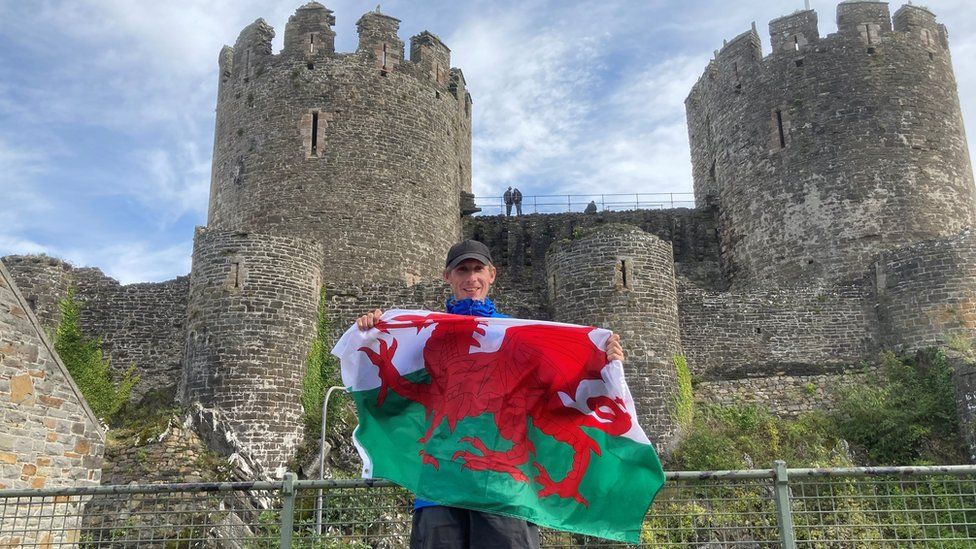 Will Renwick holding a welsh flag at Conwy castle