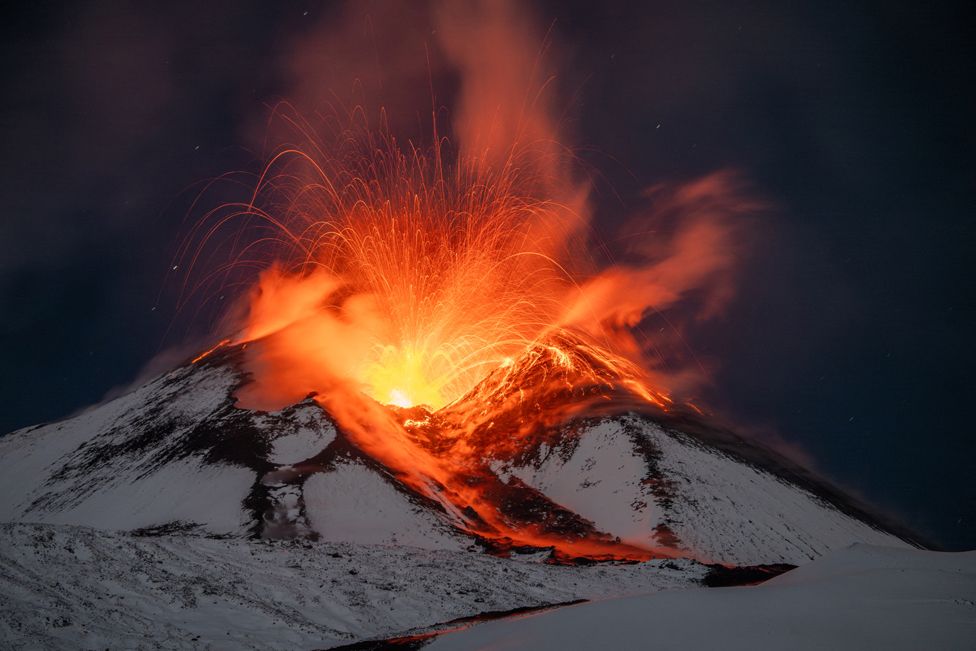 Plumes of smoke and sizzling lava rise from snow covered Mount Etna, Europe's most active volcano, as seen from Monte San Leo, Italy, November 24, 2023.