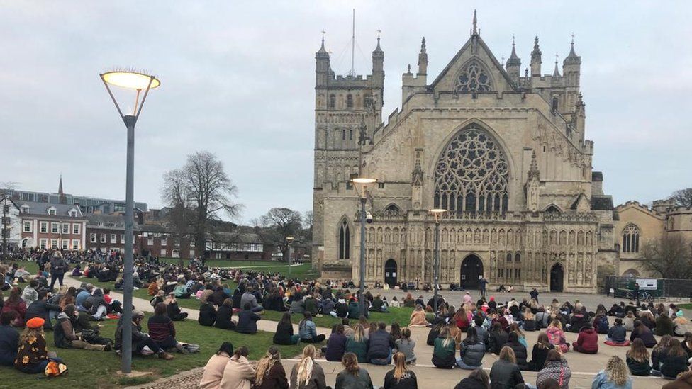 People sitting down in a vigil outside Exeter Cathedral