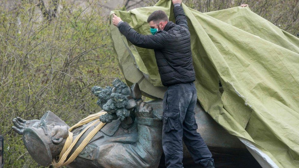 A man covers the statue of Soviet Marshal Ivan Konev laying on a truck during its removal in Prague, 3 Apr 2020