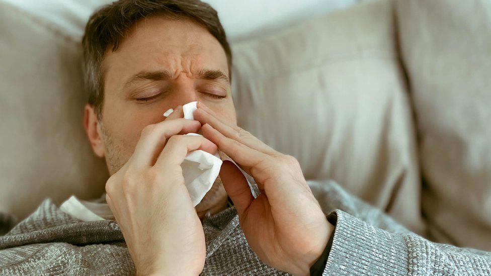 Man with Covid blowing his nose