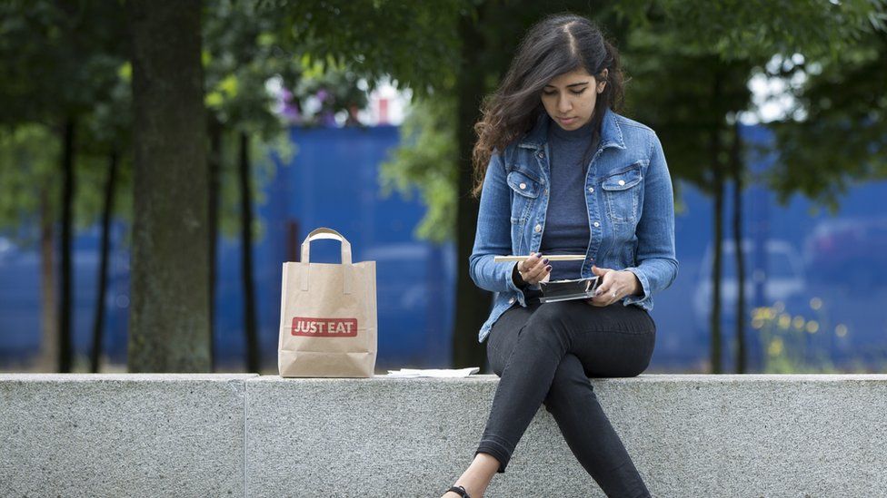 Woman eating Just Eat takeaway