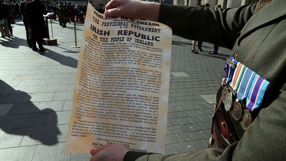 An Irish soldier holds the a copy of the 1916 Proclamation of the Irish Republic outside the General Post Office (GPO), the scene of the 1916 Easter Rising, in Dublin on March 27, 2016 as part of a programme of commemorative events to mark the 100th anniversary of the Easter Rising