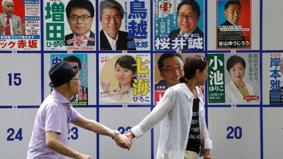 People walk past election posters in Tokyo. Photo: 31 July 2016