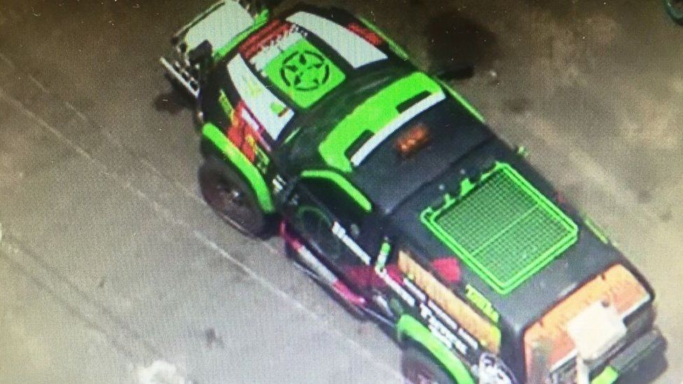 The modified truck, which is decorated in neon green, sits in a police impound lot