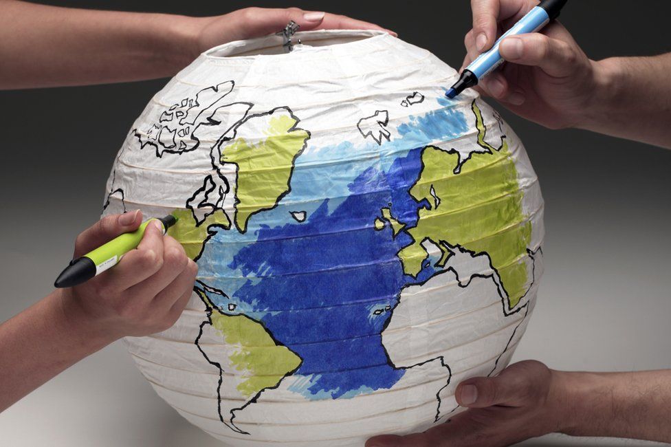 Two people colouring in paper globe